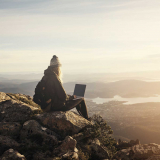girl-sitting-on-top-of-a-mountain-with-a-laptop